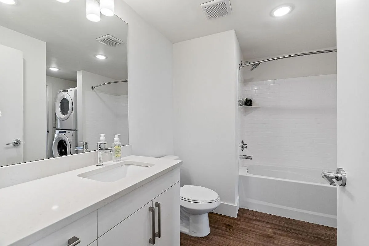 Sleek modern bathroom featuring a spacious vanity, pristine bathtub, and convenient in-unit laundry at The Richmond Apartments in Millcreek.