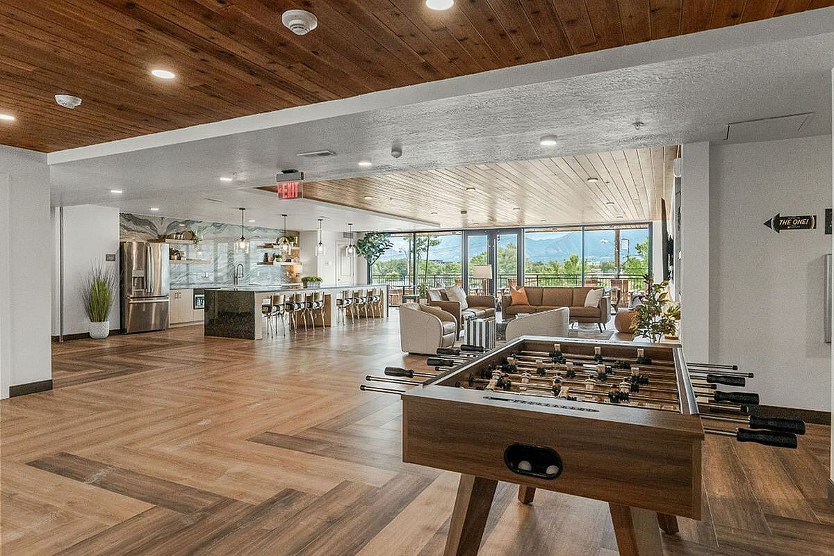 Clubroom featuring a modern kitchen, stylish seating area, and a foosball table with breathtaking mountain views  at Current Apartments in Murray Utah
