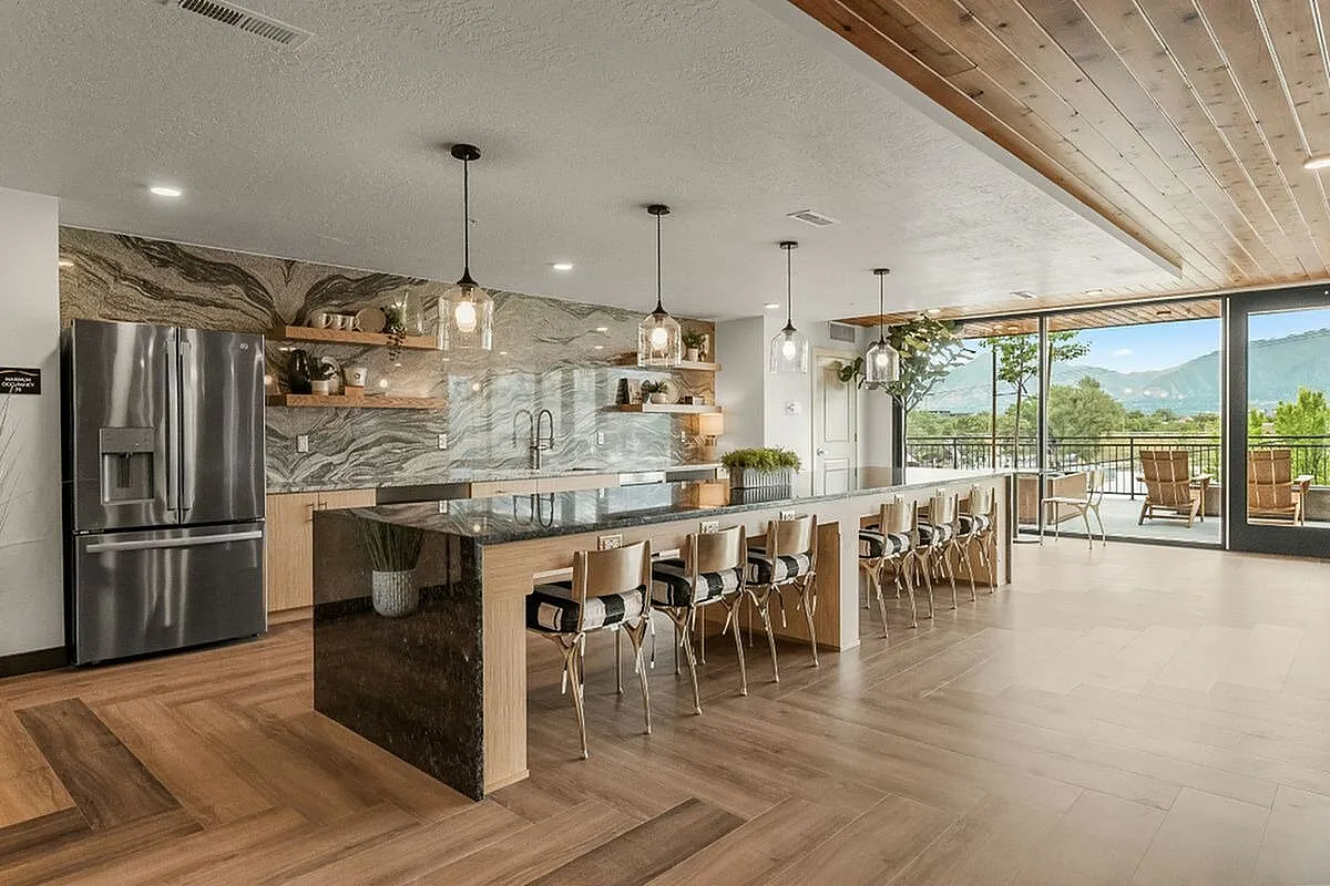 Clubroom kitchen with modern appliances, chic pendant lighting, and stunning mountain view from large windows at Current Apartments in Murray Utah