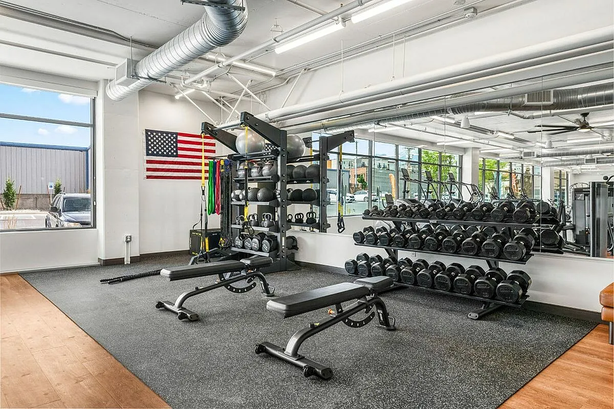 Modern fitness center with abundant natural light, featuring sleek workout benches, an array of dumbbells, and vibrant exercise equipment ready for an energizing workout  at Current Apartments in Salt Lake City Utah