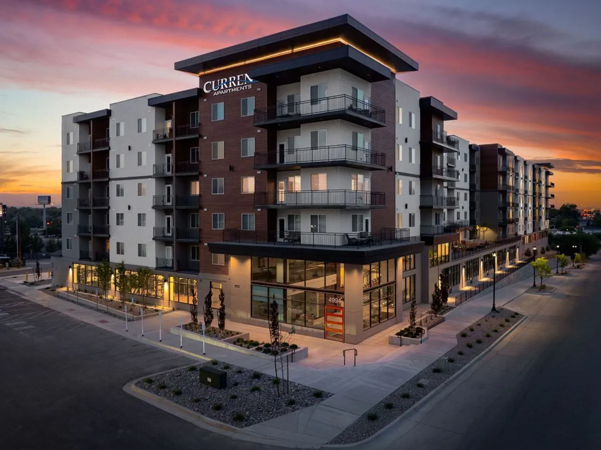 Modern luxury apartment building at sunset, featuring sleek architectural design and warm, inviting lighting at Current Apartments in Murray Utah