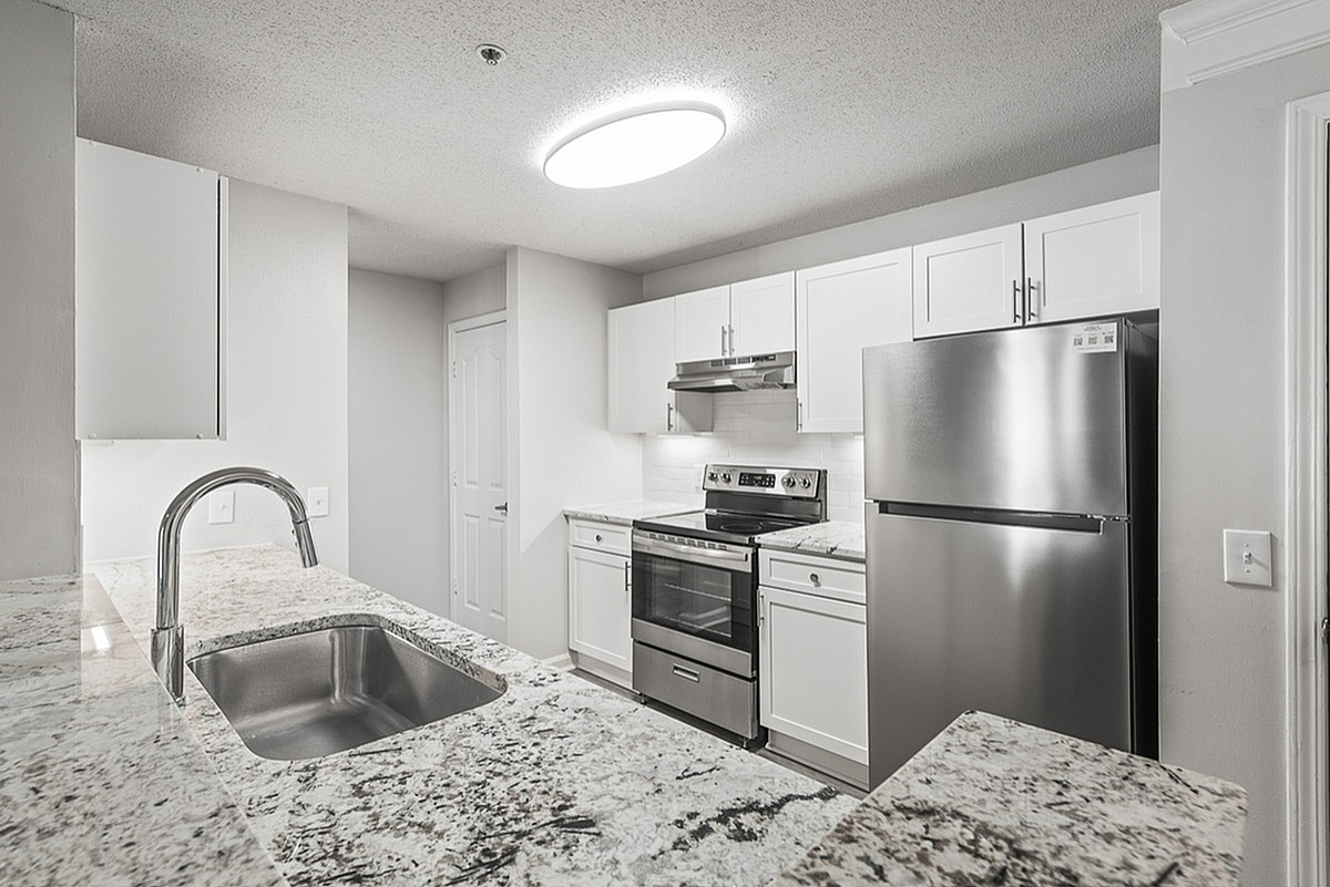 Modern kitchen with sleek stainless steel appliances and elegant granite countertops in Retreat at Peachtree City Apartments.