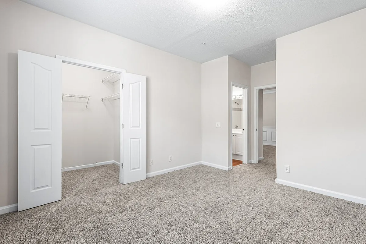 Bright and inviting bedroom at Retreat at Peachtree City Apartments with plush carpeting, walk-in closet, and en-suite bathroom, ideal for comfortable living.