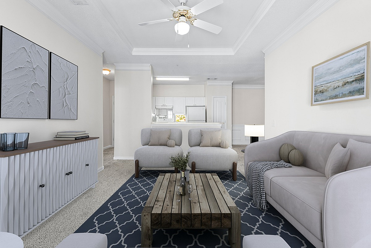 Elegant living room at Retreat at Peachtree City Apartments with modern decor, featuring plush sofas, a rustic wooden coffee table, and a stylish ceiling fan, perfect for relaxation.