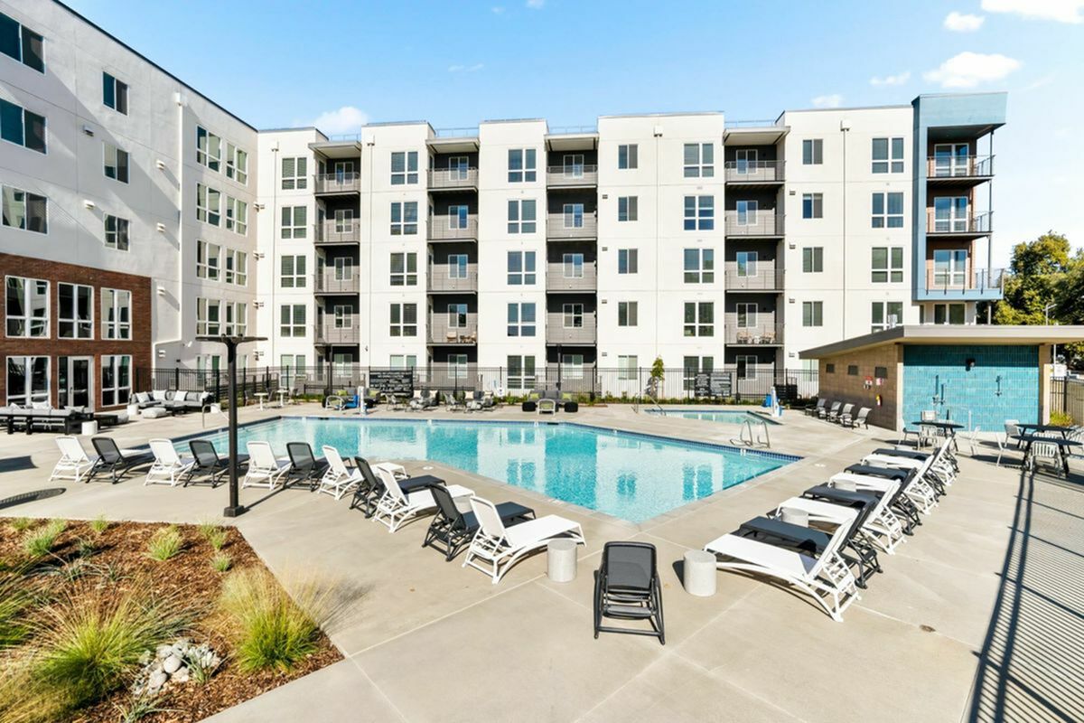 Modern apartment complex with a stunning outdoor pool area surrounded by stylish lounge chairs and contemporary architecture at 805 Riverfront Apartments in West Sacramento