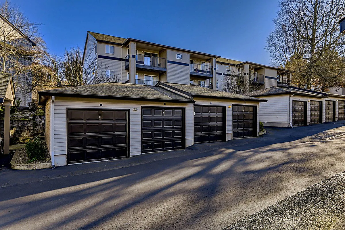 Charming apartment complex, Scott Mountain, with modern garages, surrounded by serene trees under a clear blue sky.