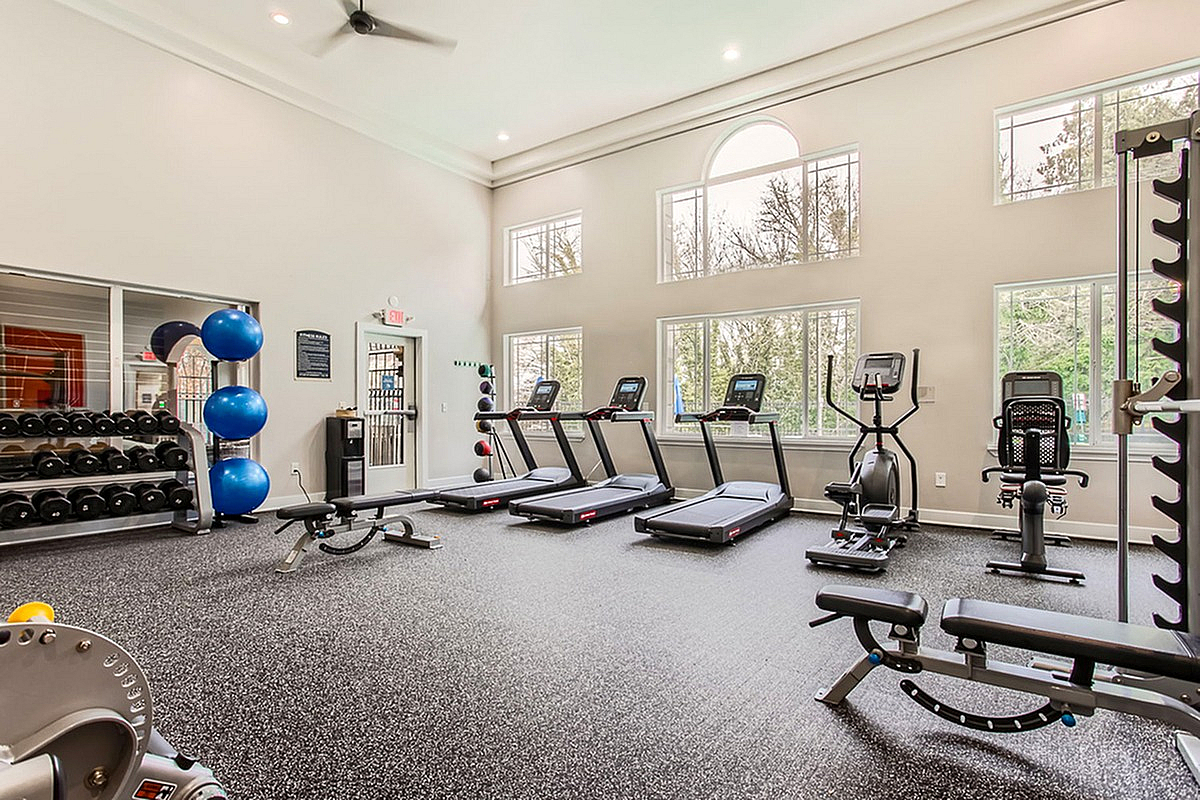 Bright and modern fitness center at Scott Mountain Apartments featuring treadmills, weights, and exercise equipment with large windows and high ceilings.