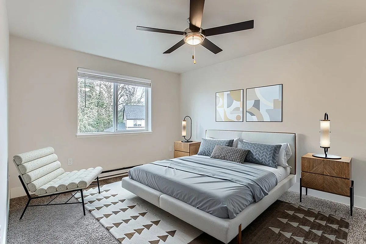 Bright and modern bedroom at Scott Mountain Apartments with elegant decor, featuring a stylish bed, contemporary artwork, and a large window offering natural light.