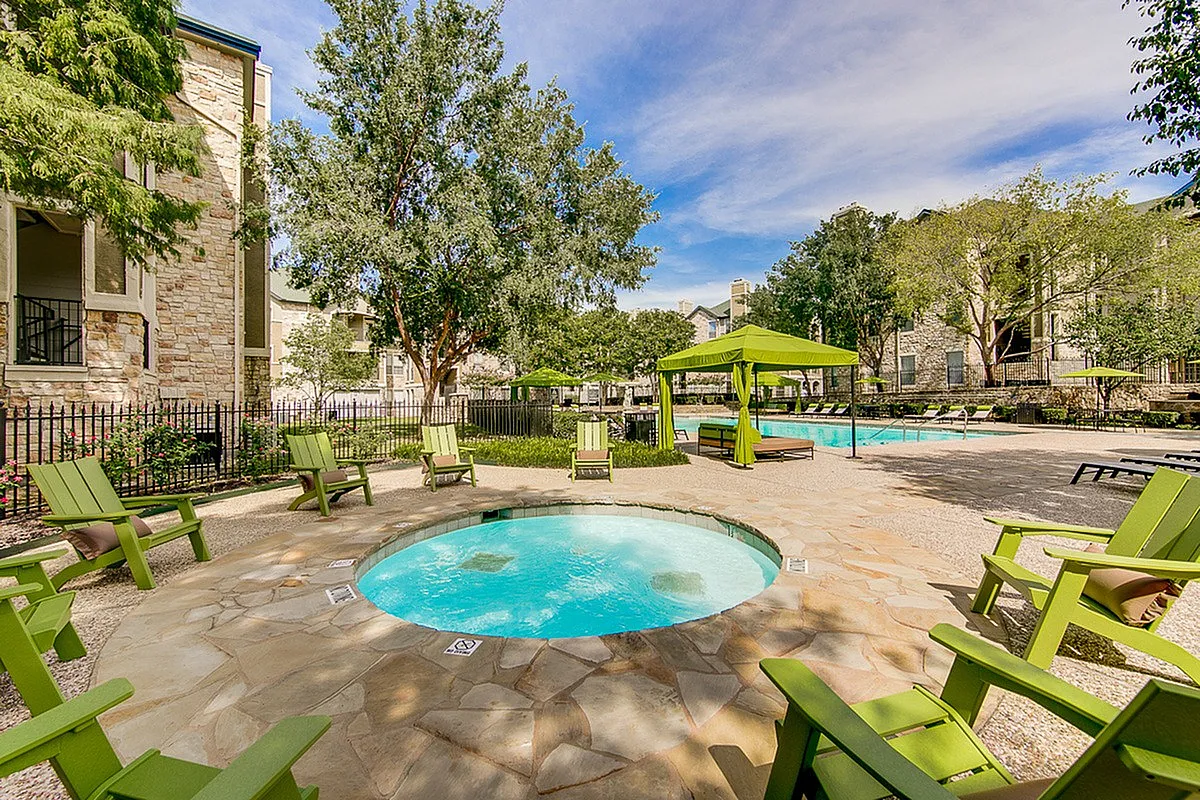 Inviting outdoor space at Stonebriar of Frisco Apartments featuring a vibrant swimming pool, cozy seating, and lush greenery, perfect for relaxation and enjoyment.