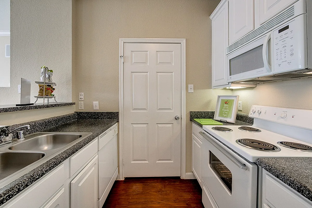 Modern kitchen at Stonebriar of Frisco Apartments with sleek granite countertops, white cabinetry, and built-in appliances for a stylish and functional space.