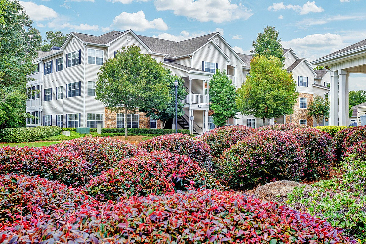 Exterior of Summer Park Apartments, a charming apartment complex with lush landscaping, vibrant flowers, and elegant architecture under a clear blue sky.