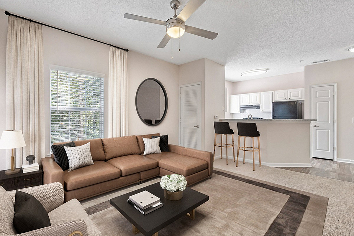 Modern living space at Summer Park Apartments with cozy brown sofa, sophisticated decor, and an inviting open-plan kitchen with bar seating.