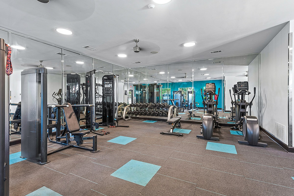 Modern fitness center at Summer Park Apartments with sleek gym equipment, mirrored walls, and vibrant blue accents.