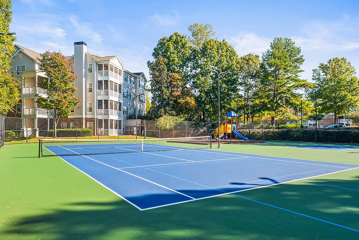 Inviting apartment complex, Summer Park, with picturesque tennis court and vibrant playground, surrounded by lush greenery.