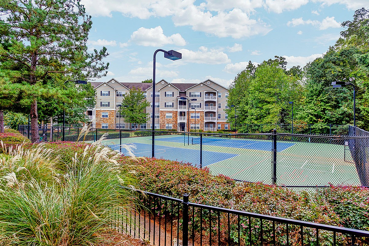 Charming apartment complex with lush greenery and a vibrant tennis court, perfect for active living and leisure at Summer Park.