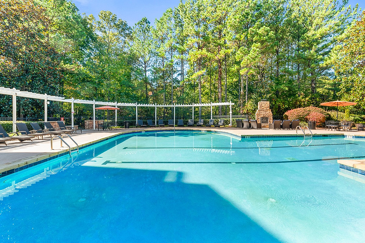 Inviting outdoor pool area with elegant lounge chairs and vibrant greenery, perfect for relaxation and leisure at Summer Park Apartments.