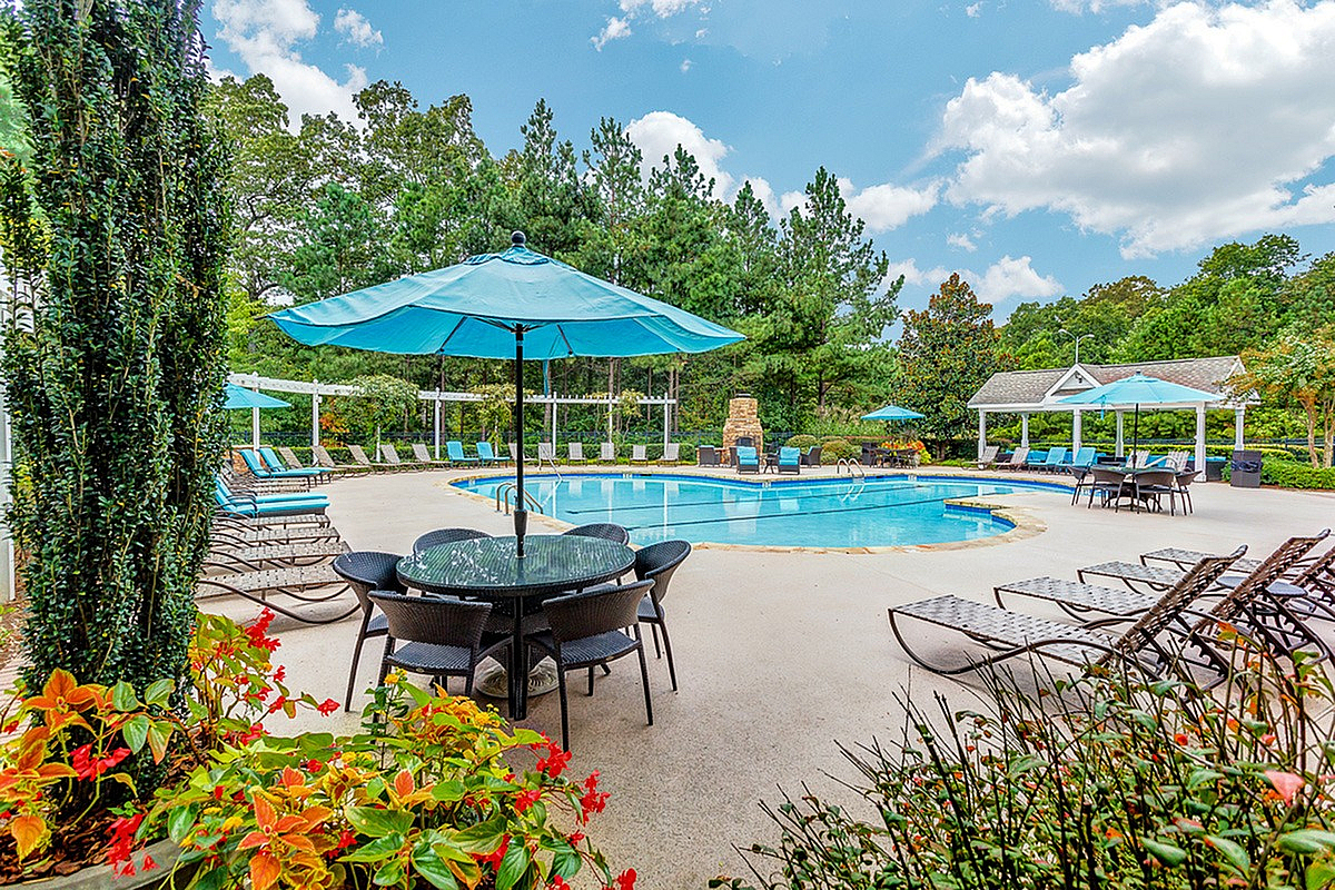 Charming outdoor pool area with lush greenery, inviting poolside loungers, and vibrant umbrellas creating a serene oasis at Summer Park Apartments.