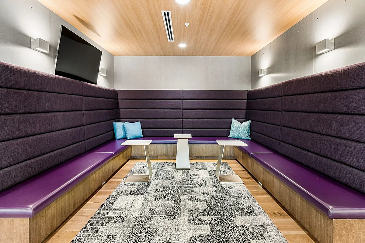 Modern conference room with plush purple seating, sleek tables, and a stylish patterned rug under warm ambient lighting  at Apt CoWork at Sugarmont Apartments in Salt Lake City