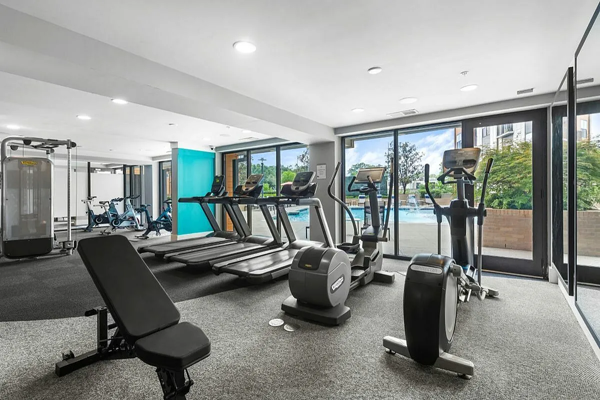 Modern fitness center featuring state-of-the-art exercise equipment with large windows overlooking a refreshing outdoor pool and lush greenery at Cottonwood Westside Apartments in West Midtown Atlanta