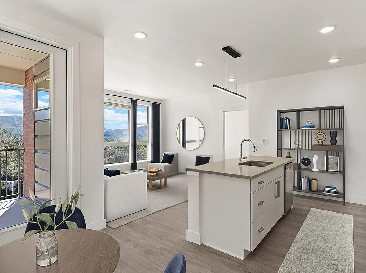 Modern open-concept living area featuring a sleek kitchen island, chic seating, and large windows with stunning mountain views at The Richmond in Millcreek.