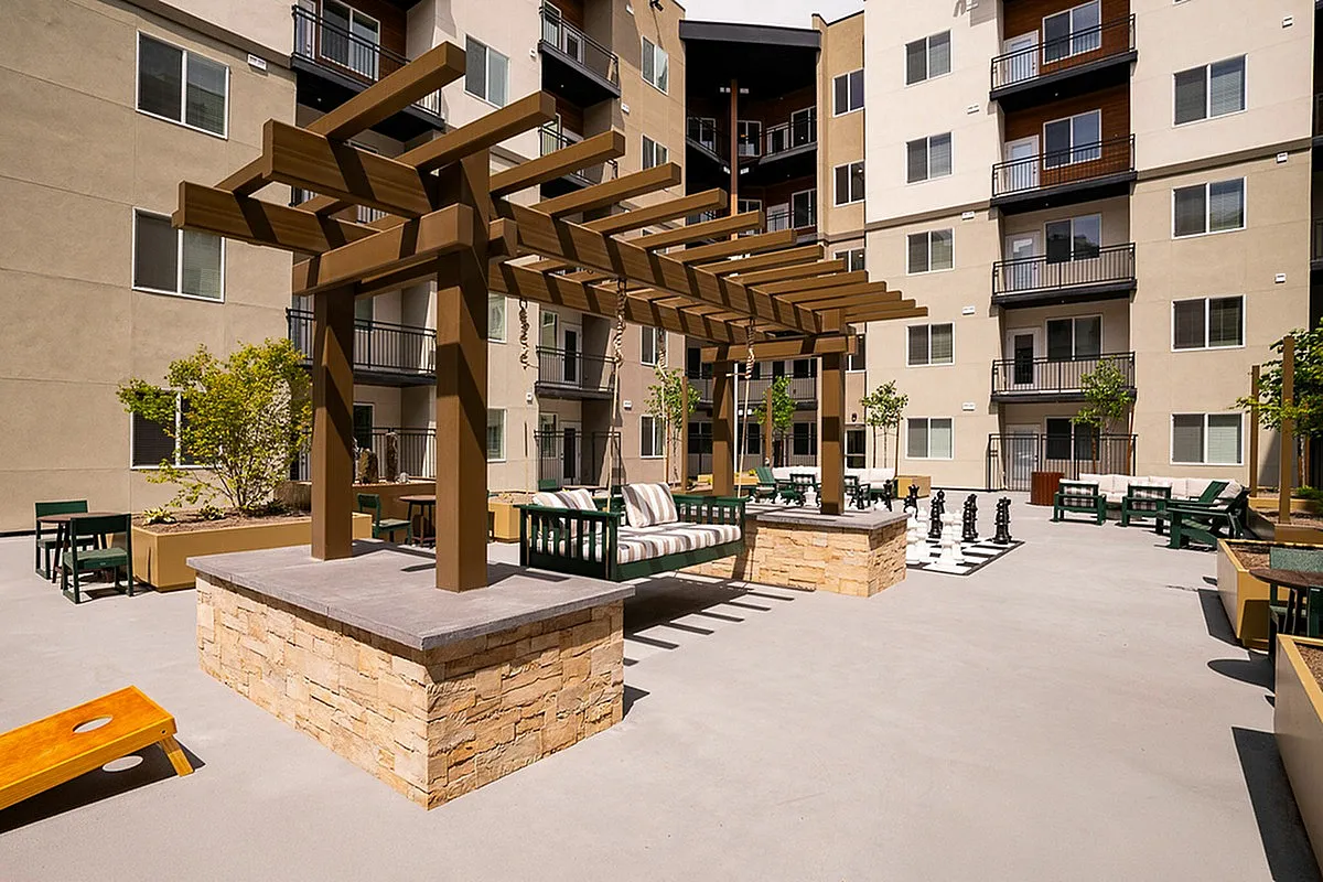 Courtyard at Current Apartments featuring a stylish pergola, modern seating, a life-sized chess set, and a zen garden.