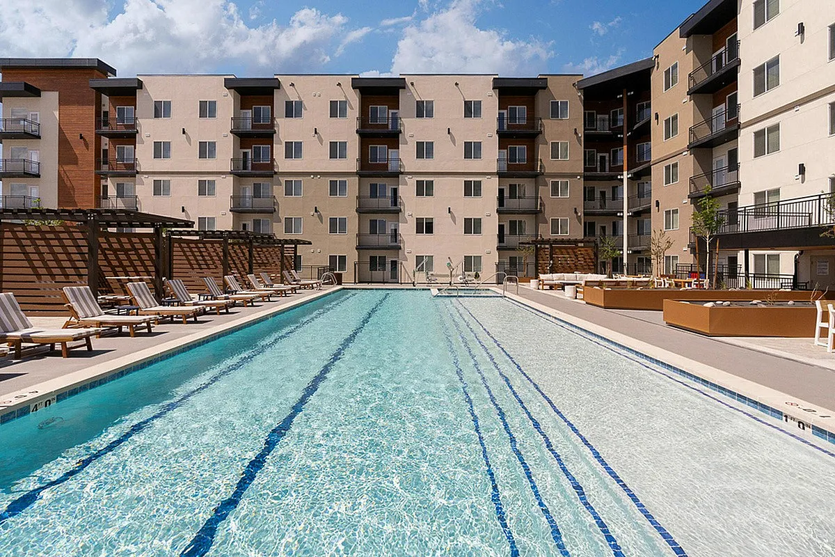 Luxury apartment complex in Murray, UT with a large, inviting swimming pool surrounded by comfortable loungers and modern architecture at Current Apartments.