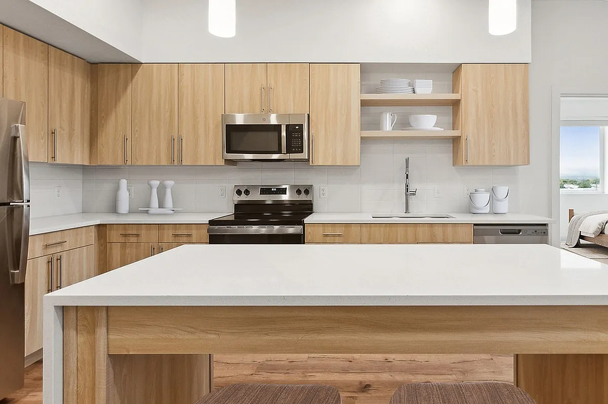 Modern kitchen with sleek stainless steel appliances, elegant wood cabinetry, and a spacious island at Current Apartments in SLC.
