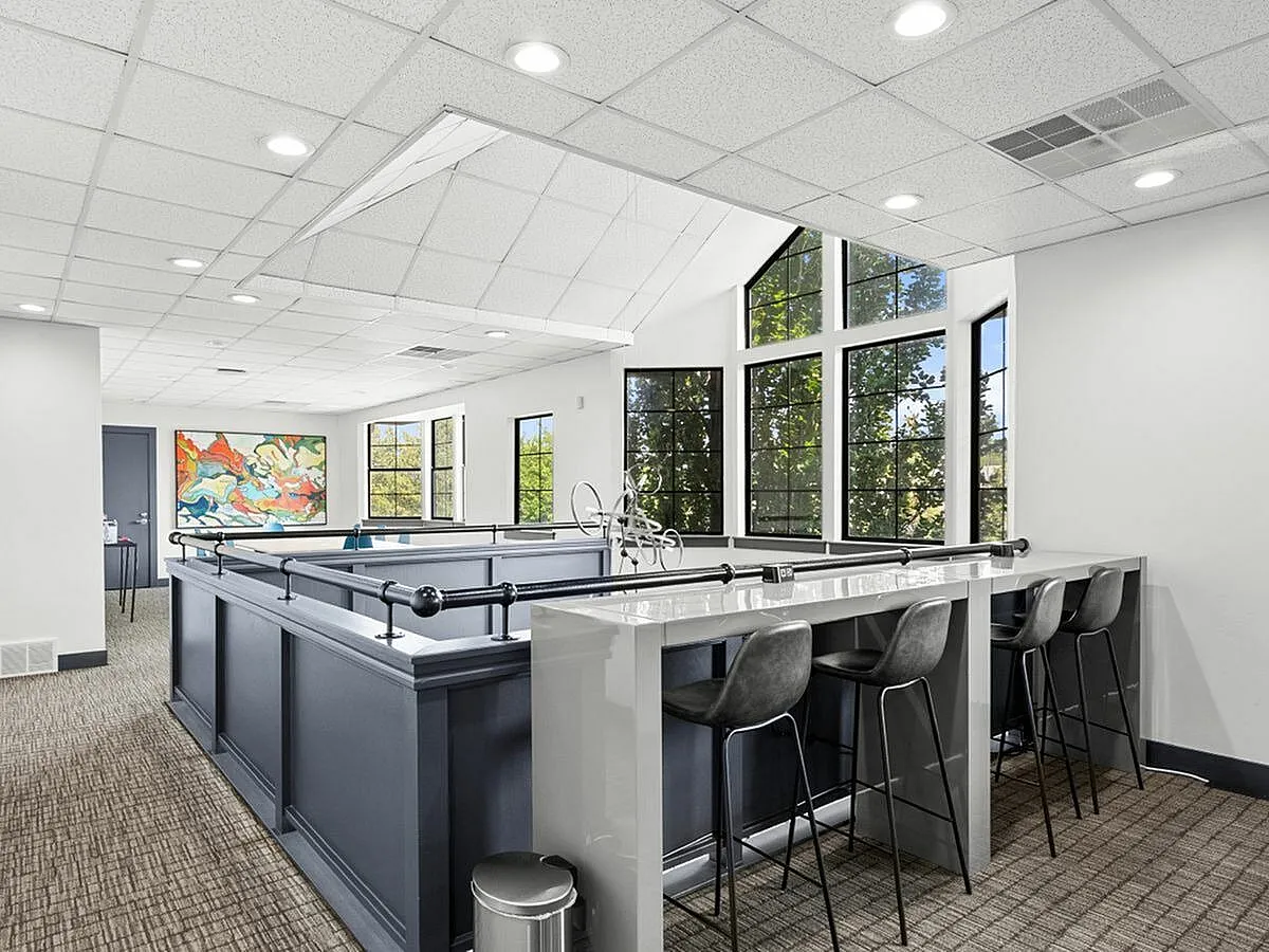Contemporary and inviting communal lounge with modern high stools, vibrant artwork, and large sunlit windows at Apt CoWork at Cottonwood Apartments in SLC