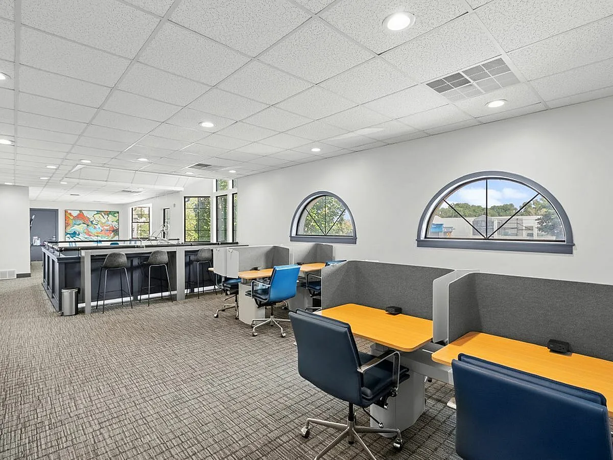 Modern open-plan coworking space with sleek desks, stylish bar seating, and vibrant wall art, offering a bright and collaborative work environment  at Apt CoWork at Cottonwood Apartments in SLC