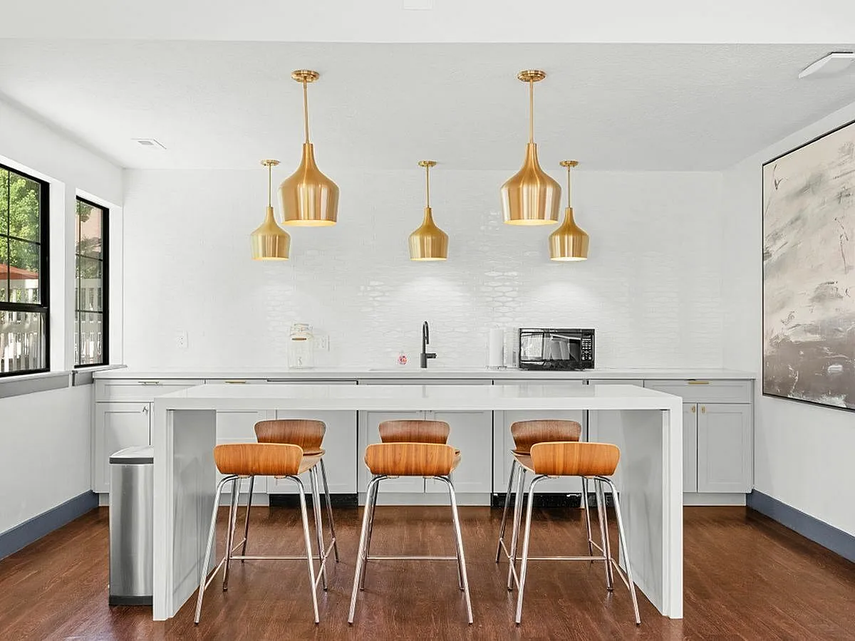 Chic modern kitchen with elegant golden pendant lights, sleek white cabinetry, and stylish wood-accented bar stools  at Apt CoWork at Cottonwood Apartments in Salt Lake City