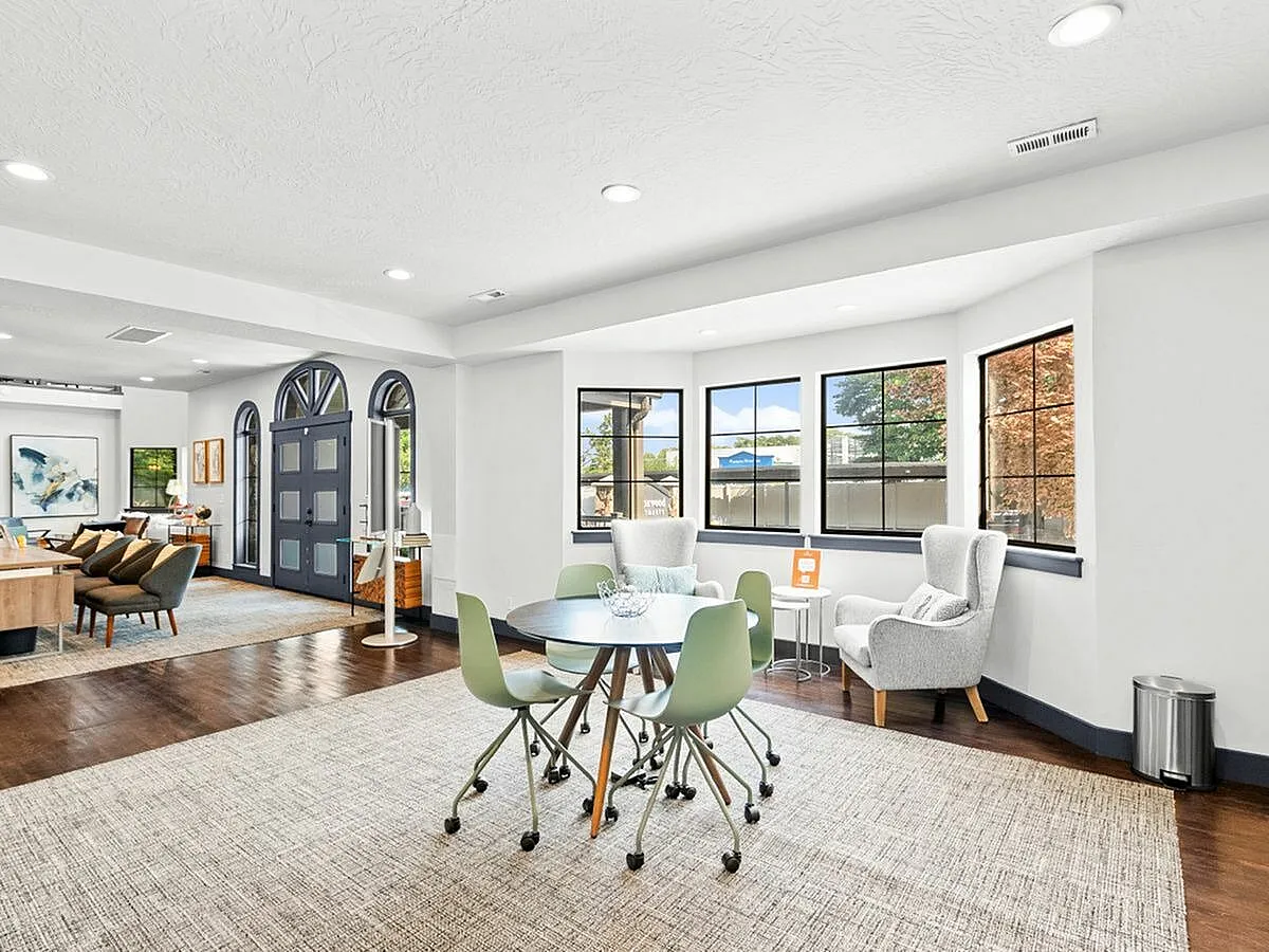 Chic and spacious living area with modern furnishings, large windows, and inviting seating, perfect for relaxation and entertaining at Apt CoWork at Cottonwood Apartments in Salt Lake City