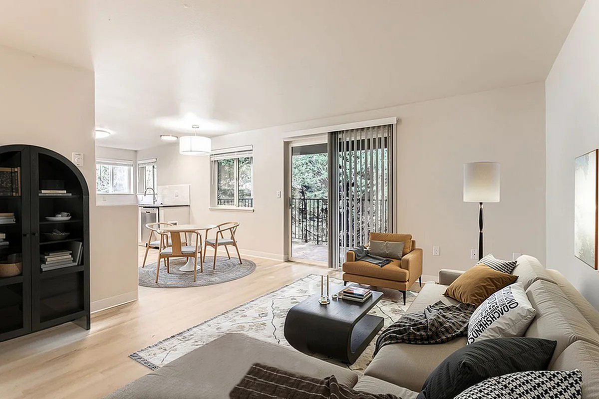 Bright, open-concept living area with modern furniture, sleek kitchen, and natural light streaming through large windows at Scott Mountain Apartments in Portland OR.