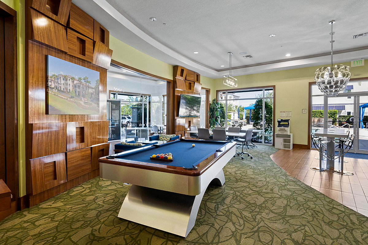Luxurious recreational room featuring a sleek pool table, elegant decor, and ample natural light at Apt CoWork at The Marq Highland Park in Tampa Florida