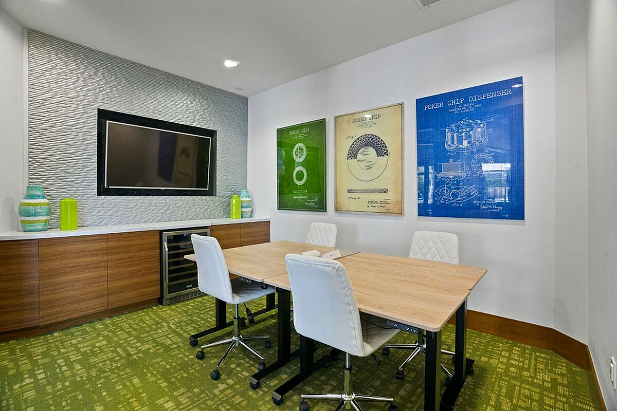 Chic modern rentable conference room with stylish wall art, a sleek TV, and comfortable white seating around a wooden table at Apt CoWork at The Marq Highland Park in Westchase Tampa
