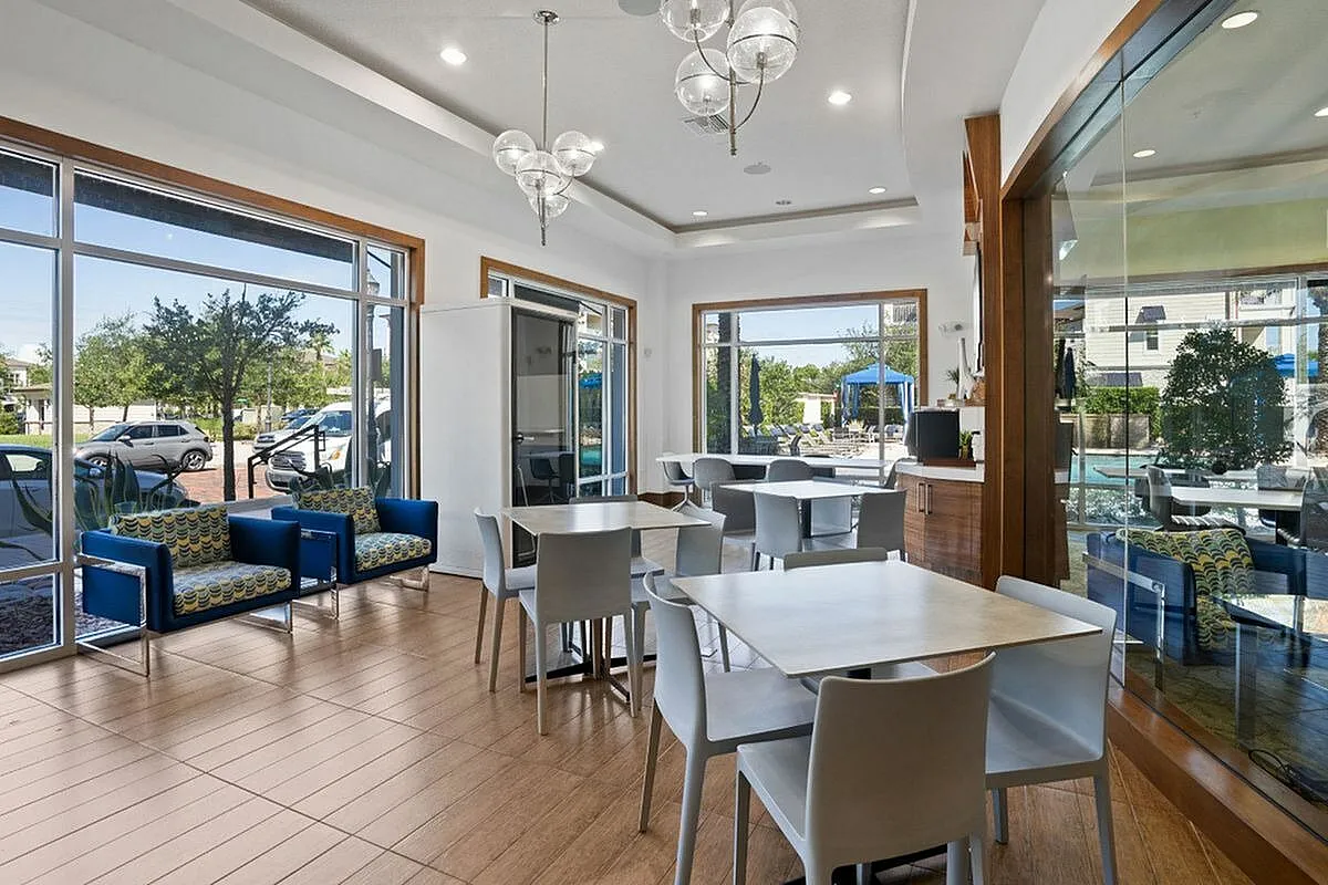 Bright and elegant meeting area featuring modern furniture, stylish lighting, and large windows with a pool view at the Marq Highland Park Apt CoWork in Westchase Tampa