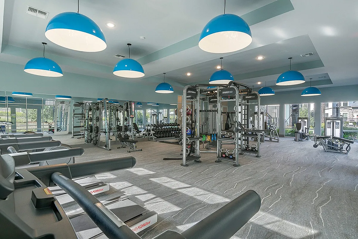 Vibrant and modern fitness center with state-of-the-art equipment, bright lighting, and spacious interiors at Cottonwood Clermont Apartments.
