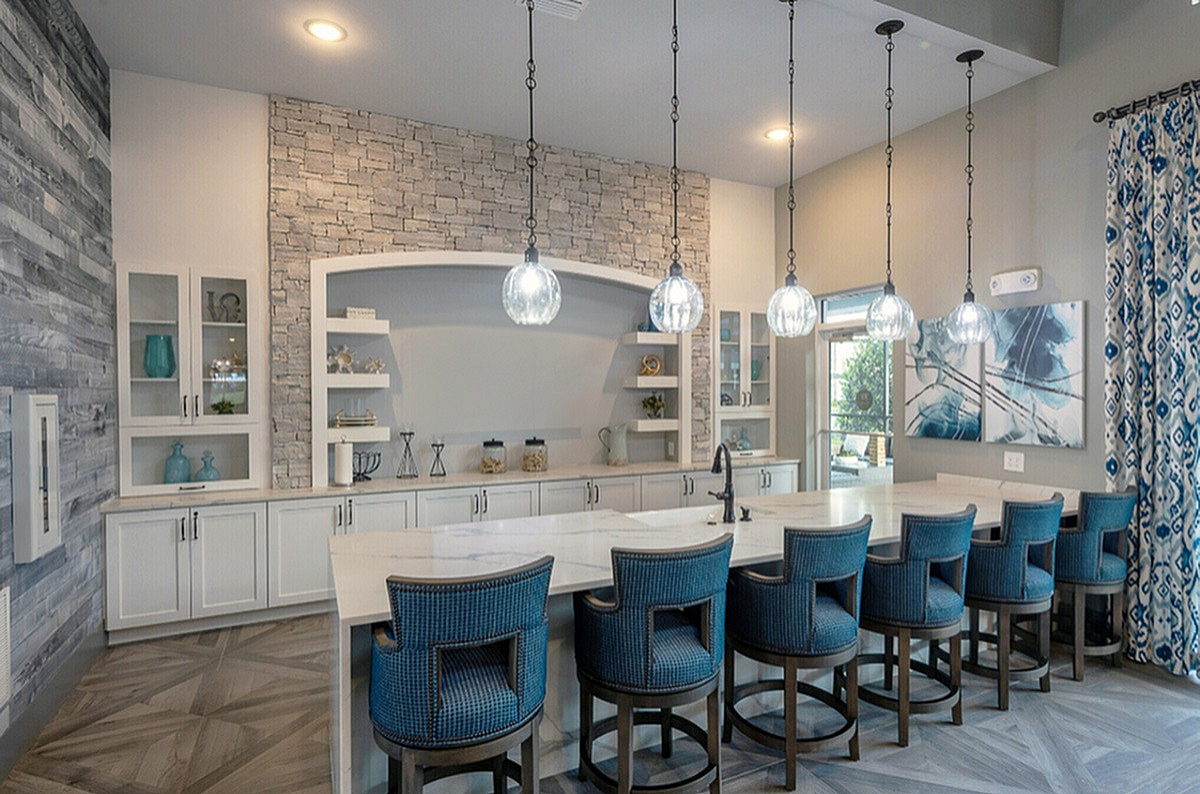 Chic modern kitchen in Cottonwood Clermont's Clubroom with a stylish island, elegant pendant lighting, and comfortable blue bar chairs, perfect for entertaining.