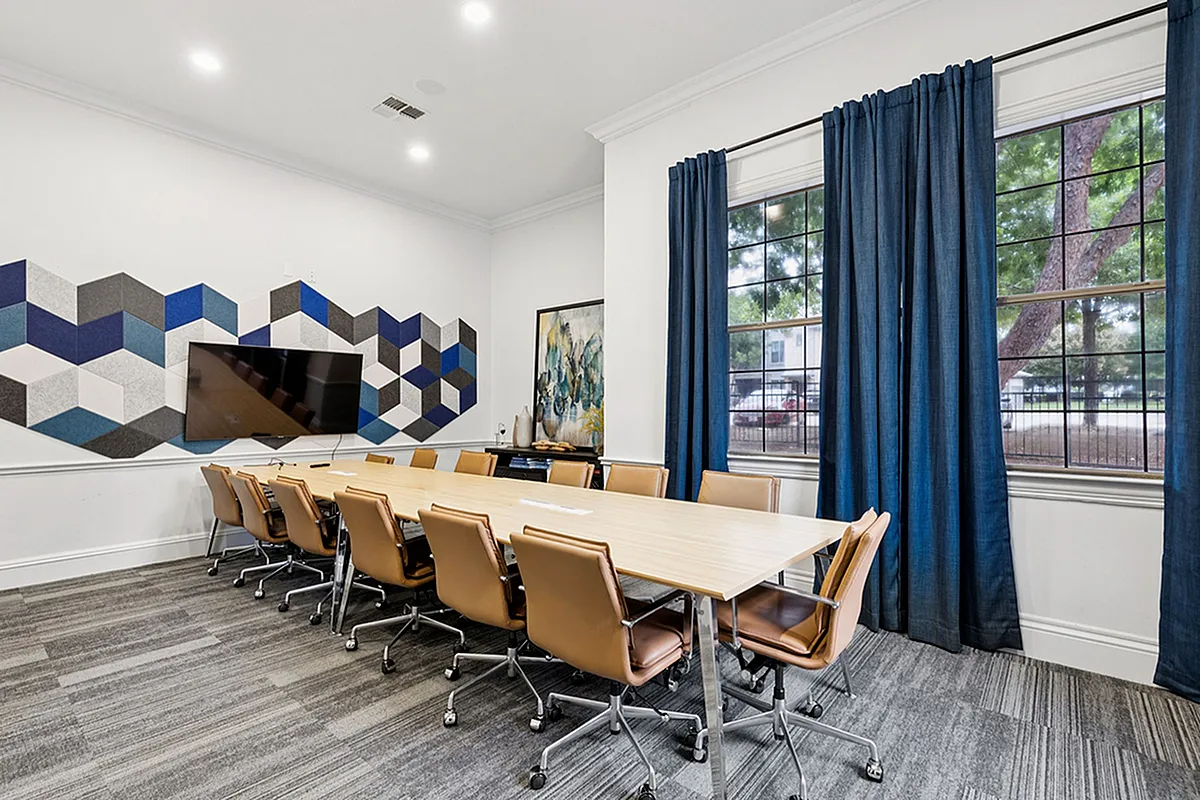 Modern conference room with a sleek long table, comfortable leather chairs, and a vibrant geometric wall design.