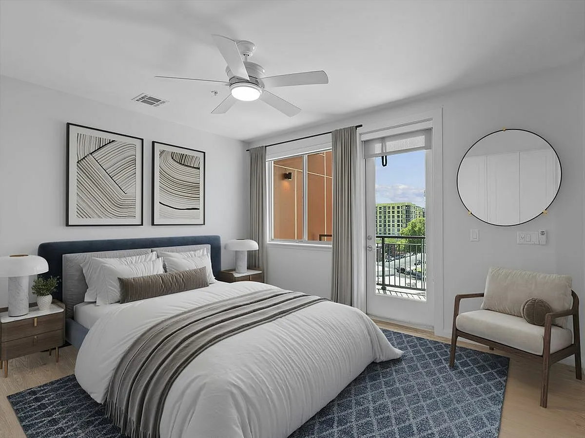 Elegant bedroom with a plush king-sized bed, modern decor, and a serene balcony view, offering a sophisticated urban retreat at Sugarmont Apartments in Sugarhouse Utah