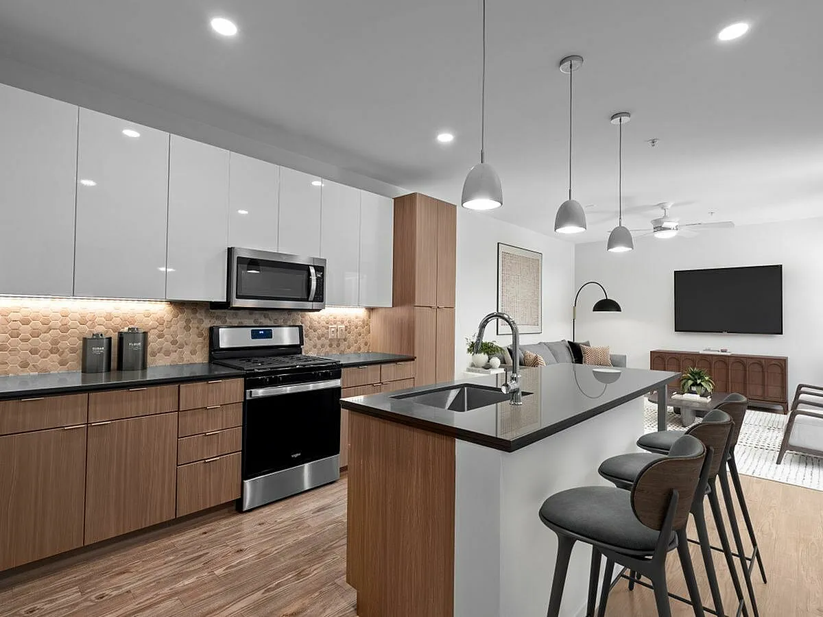 Sleek modern kitchen with island seating, stainless steel appliances, and open layout connecting to stylish living area at Sugarmont Apartments in Sugarhouse Utah