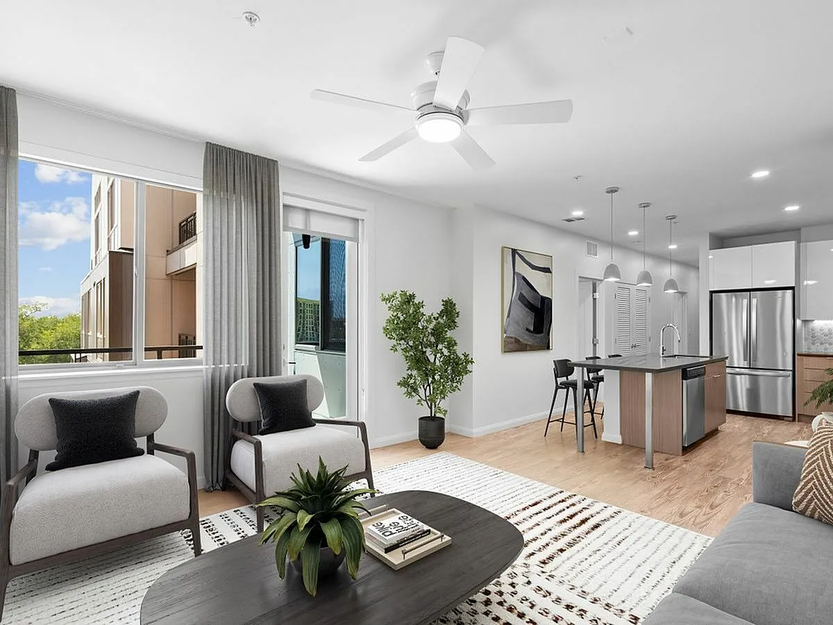 Bright and modern open-plan living room with stylish furnishings and a sleek kitchen island, featuring large windows for natural light at Sugarmont Apartments in Sugarhouse Utah