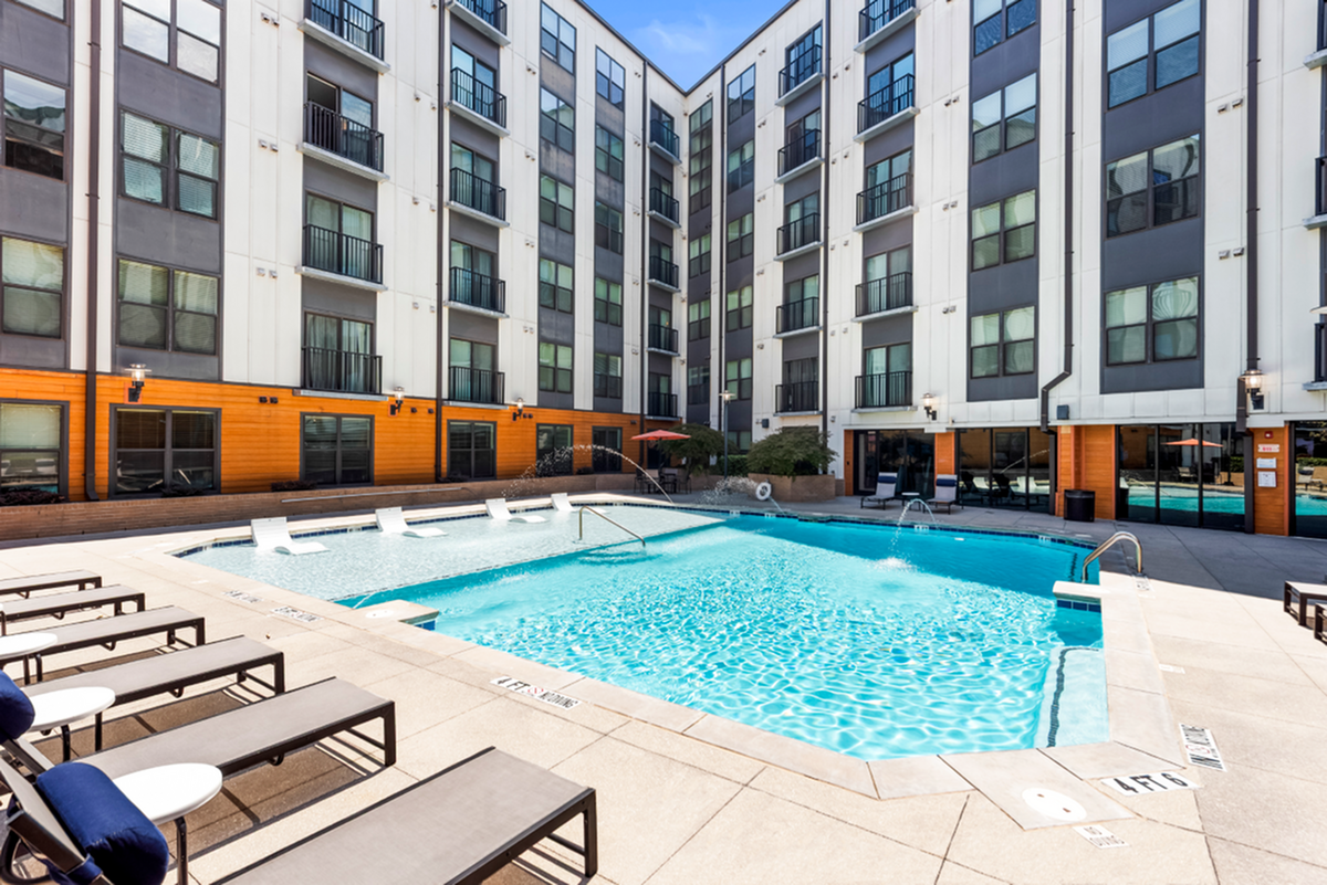 Luxurious apartment complex with a sparkling outdoor pool, sun loungers, and modern architecture at Cottonwood Westside Apartments in West Midtown Atlanta