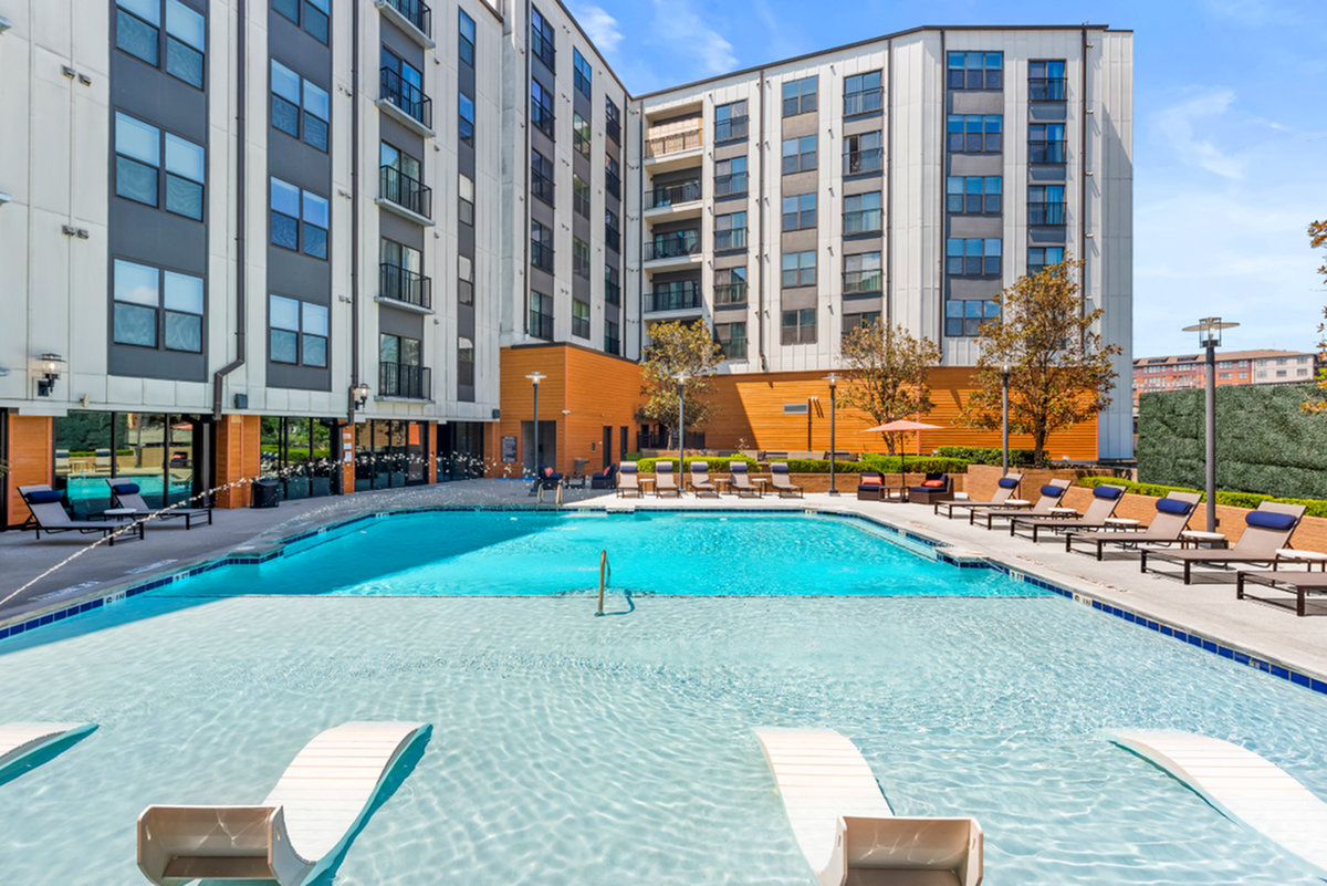 Luxurious apartment complex with a sparkling resort-style swimming pool surrounded by chic lounge chairs and modern architecture at Cottonwood Westside Apartments in West Midtown