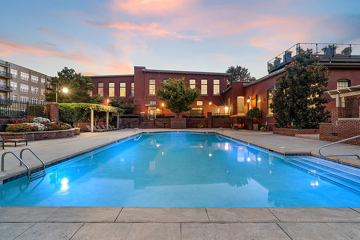Charming apartment complex featuring a stunning outdoor pool with elegant brick architecture and lush landscaping, perfect for relaxation at Alpha Mill Apartments in NODA Charlotte, NC