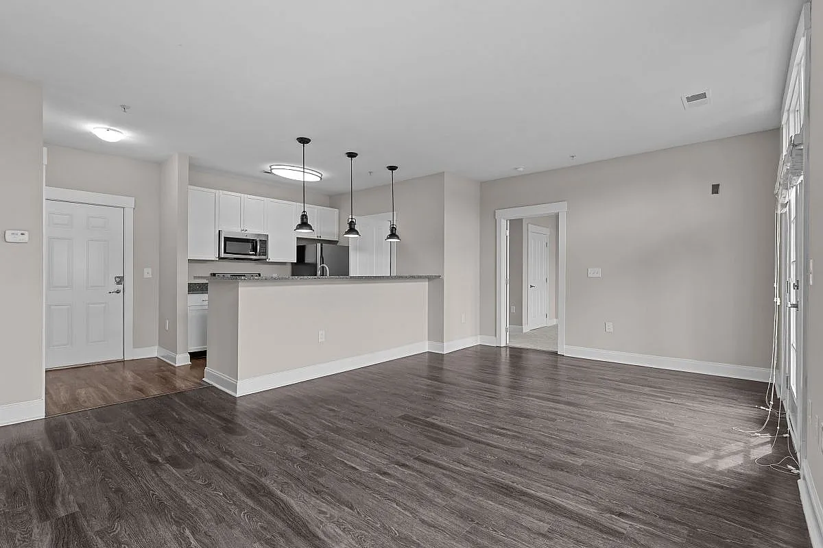 Modern open-concept apartment with elegant hardwood floors, stylish kitchen featuring pendant lighting, and abundant natural light Garden Style Bedroom at Alpha Mill Apartments in NODA Charlotte.