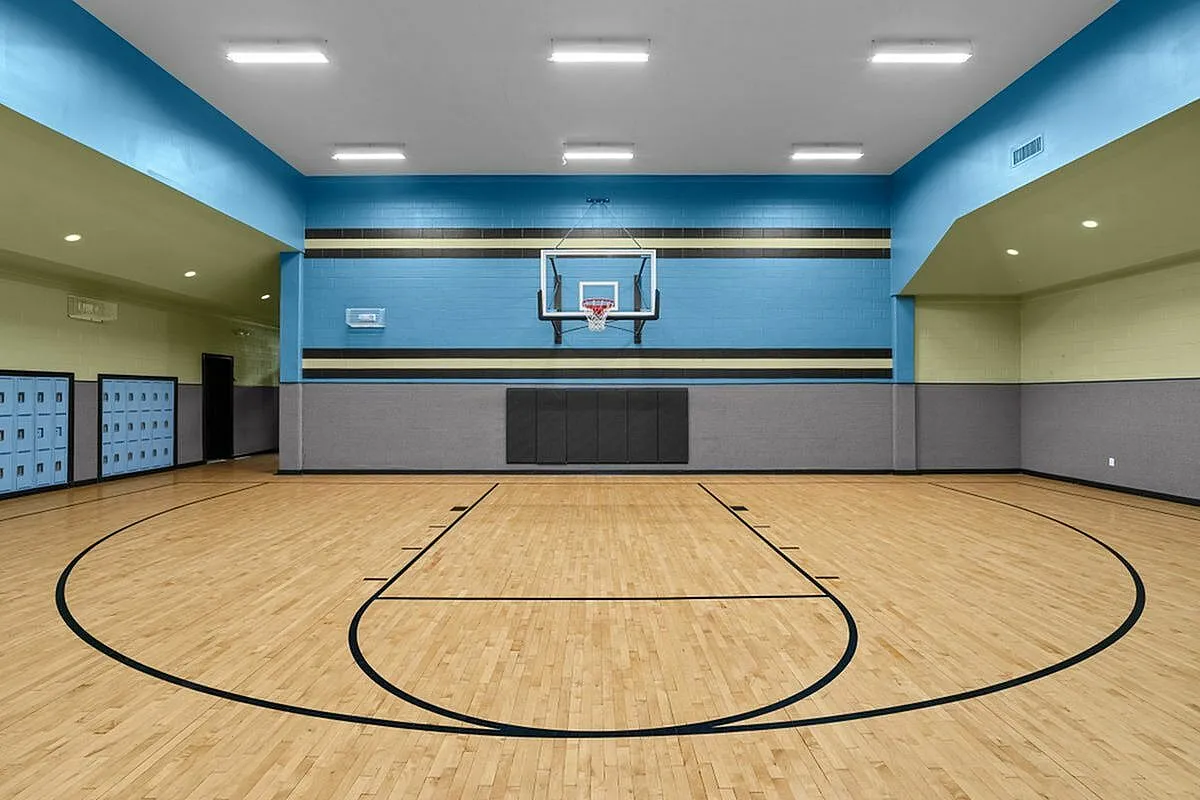 Modern indoor basketball court with polished hardwood floors and vibrant blue accents, offering perfect recreational space at Cottonwood Reserve in Charlotte, NC