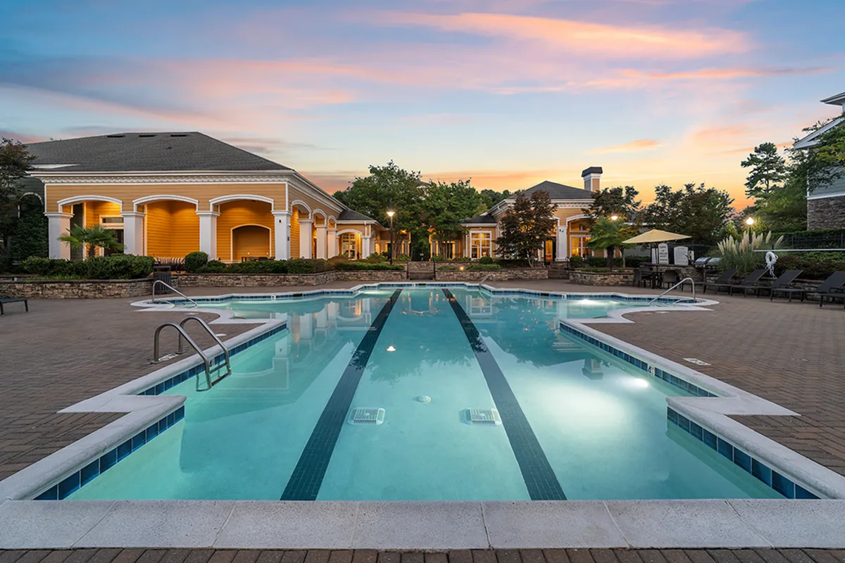 Luxurious apartment complex with a sparkling pool and elegant clubhouse against a stunning sunset backdrop at Cottonwood Reserve in Steel Creek Charlotte NC