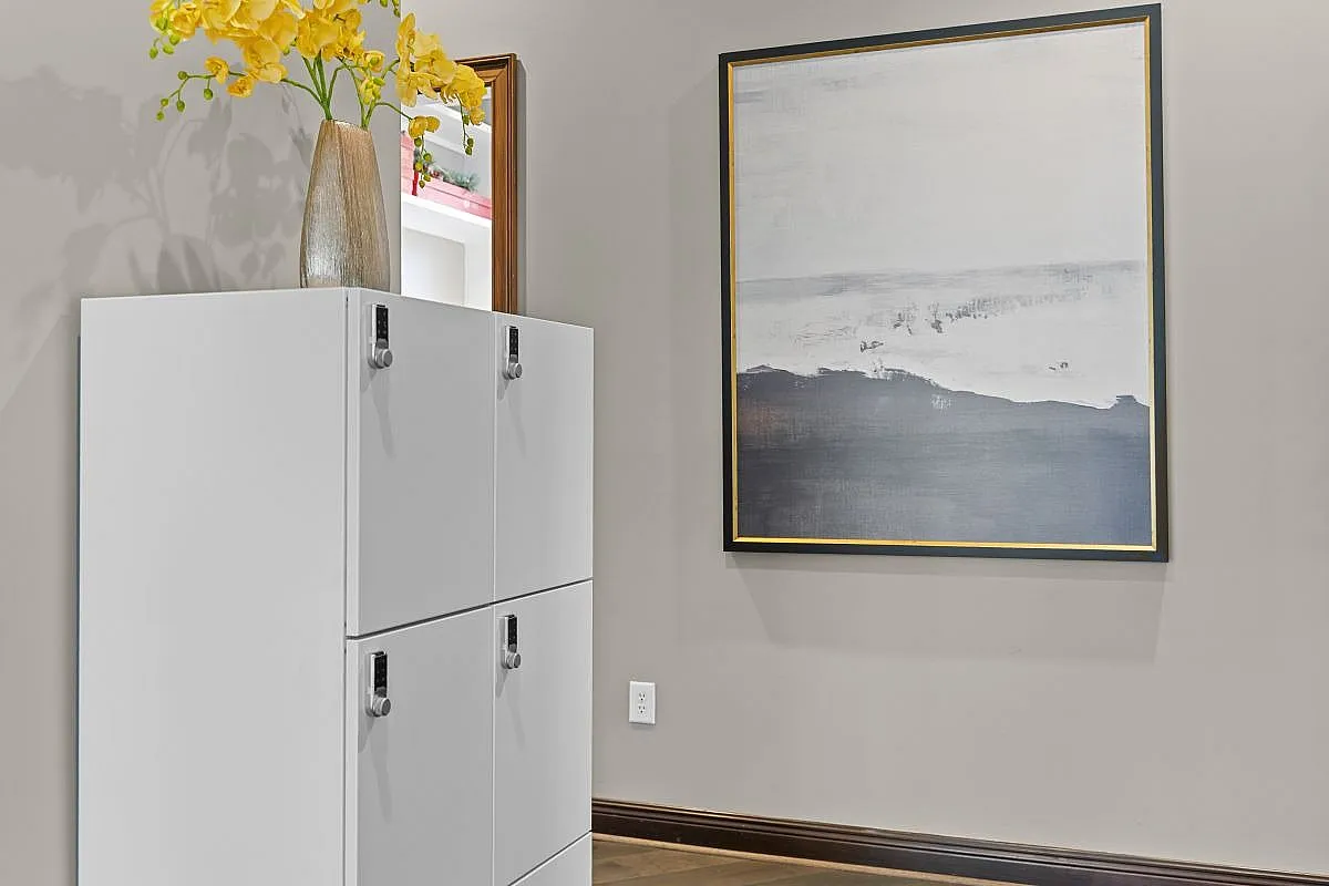 Elegant interior featuring a modern white storage cabinet, vibrant yellow flowers in a stylish vase, and a contemporary abstract painting at Apt CoWork in Charlotte, NC