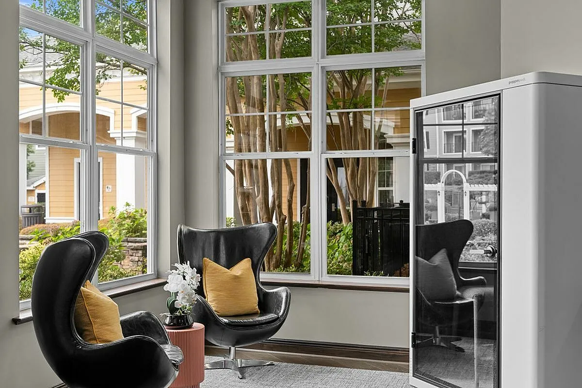 Privacy Pod with modern leather chairs, elegant decor, and large windows highlighting beautiful garden views at Apt CoWork in Charlotte, NC