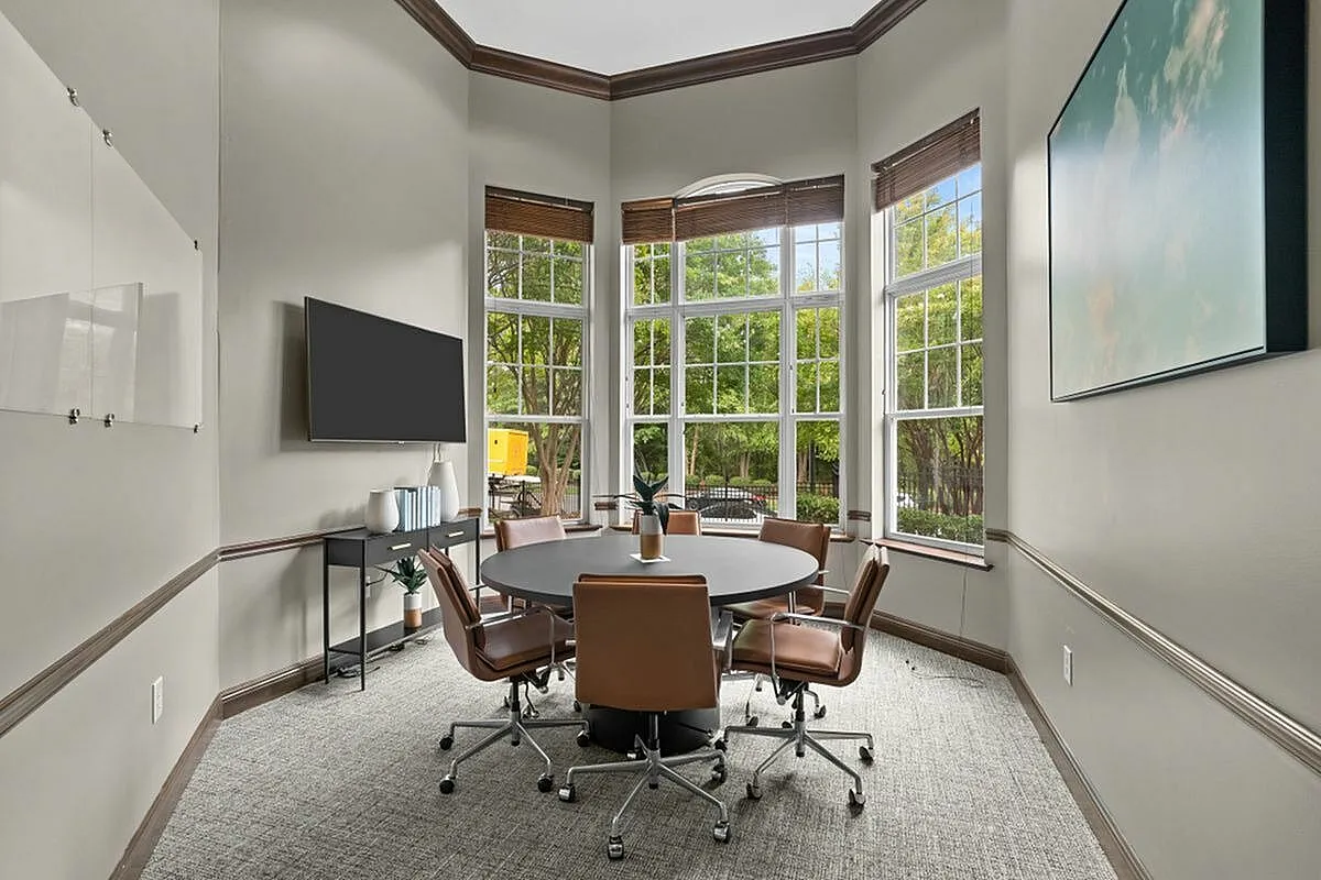 Elegant conference room with a round table, stylish leather chairs, large windows for natural light, and modern decor at Apt CoWork in Charlotte, NC